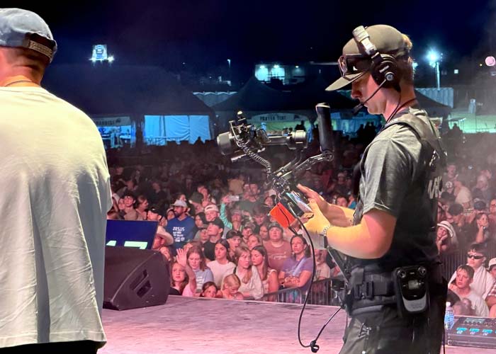 Camera operator running wireless gimbal at live sporting event or concert